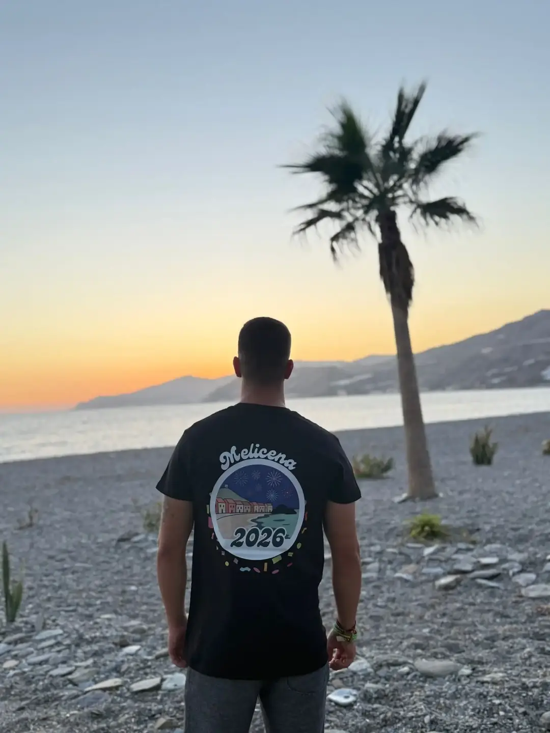 Juan con la camiseta negra de Melicena, trasera. La camiseta muestra una ilustración del pueblo por la noche.